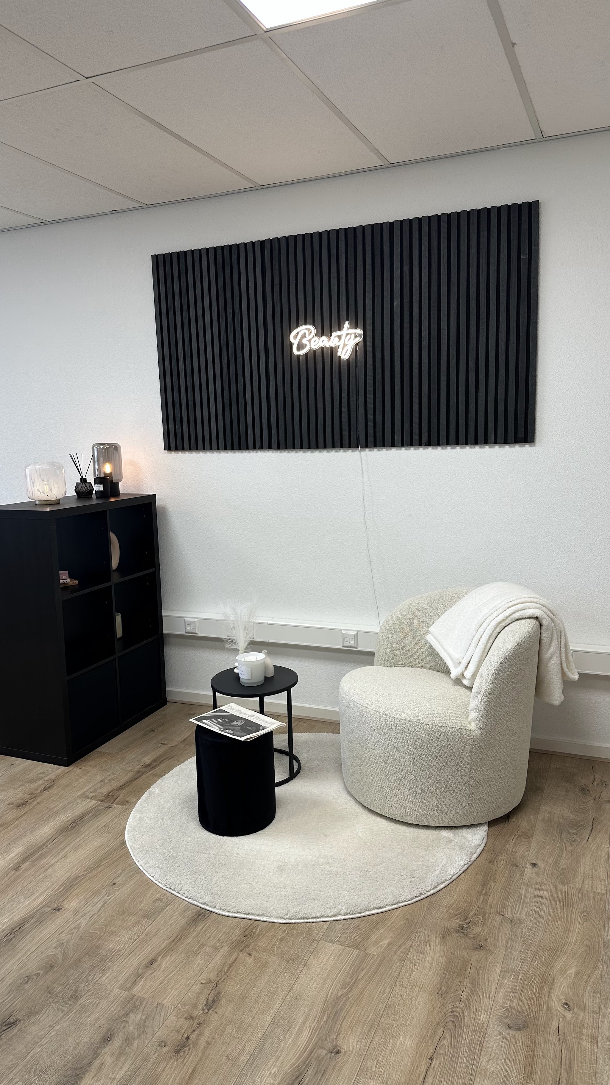 Zithoek met witte fauteuil en zwarte lamellenwand met lichtreclame