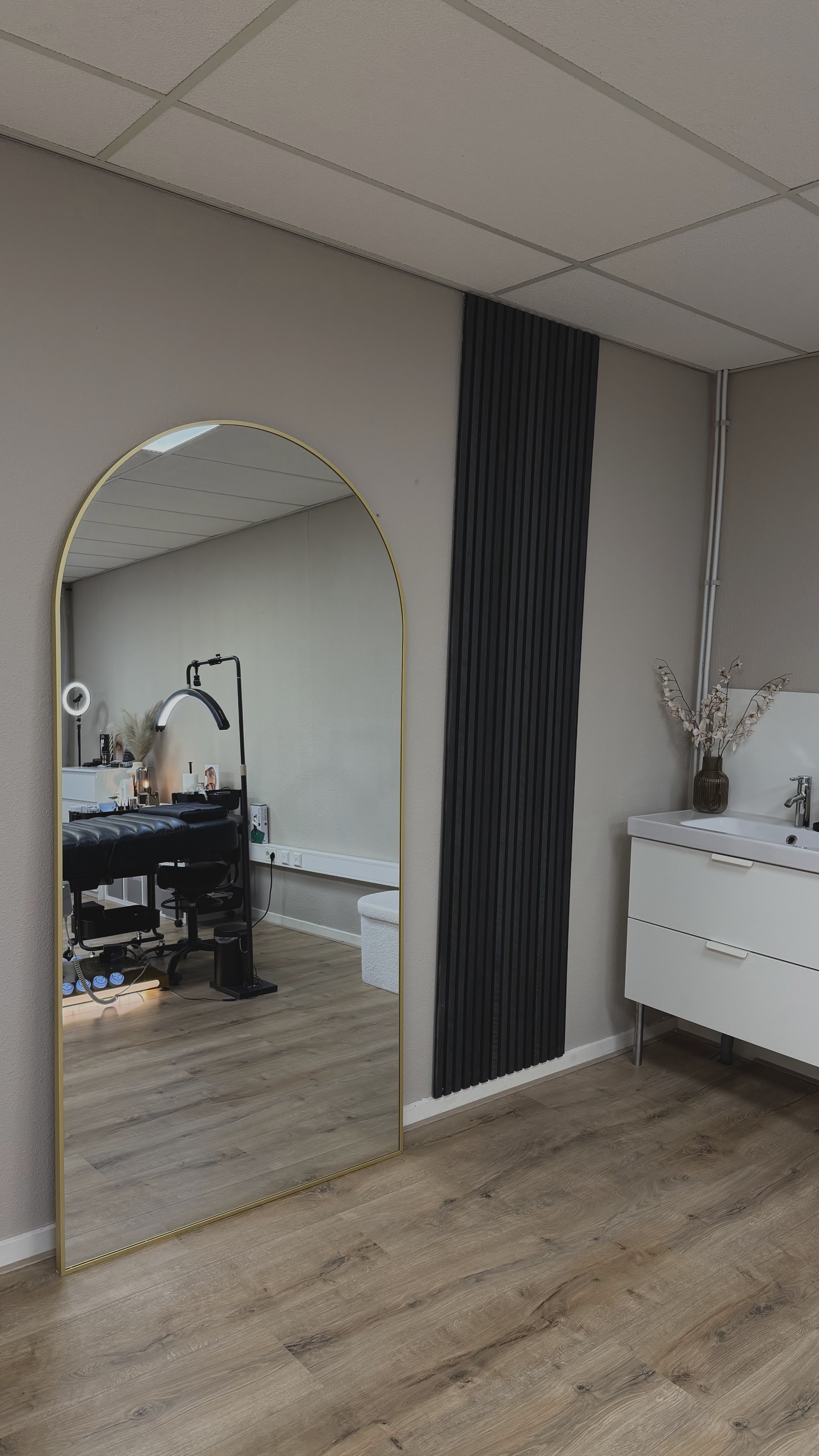 Grote gouden boogspiegel in de salon, met de behandelruimte in de reflectie